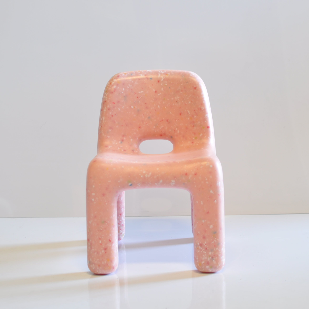 Pink confetti chair on a white surface with a light gray background
