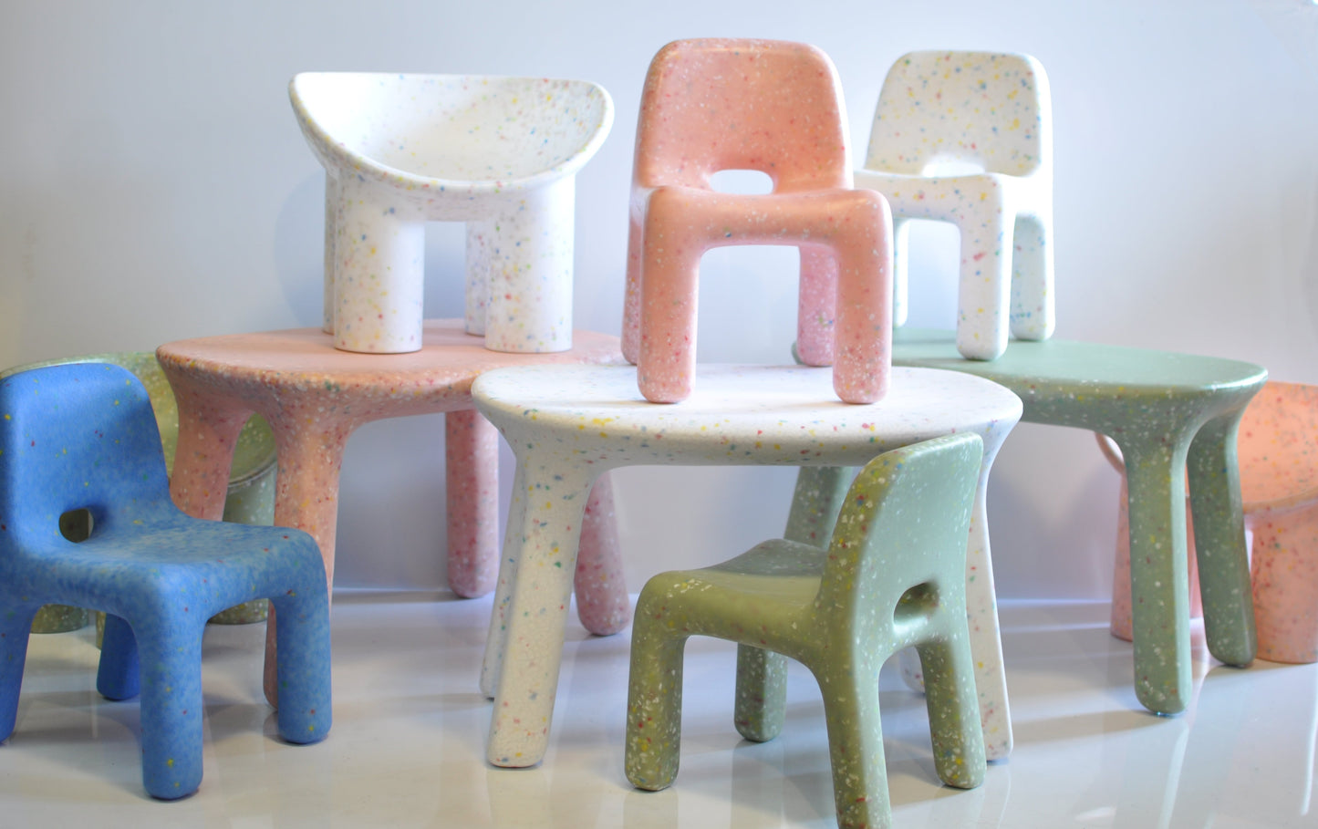Colorful confetti speckles chairs on a white surface with a light gray background
