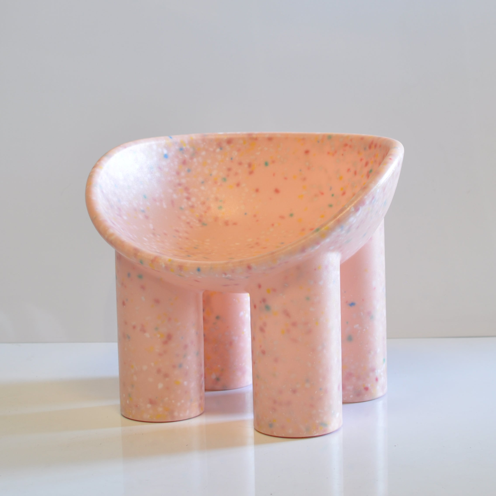 Pink speckled kids chair on a white surface with a light gray background