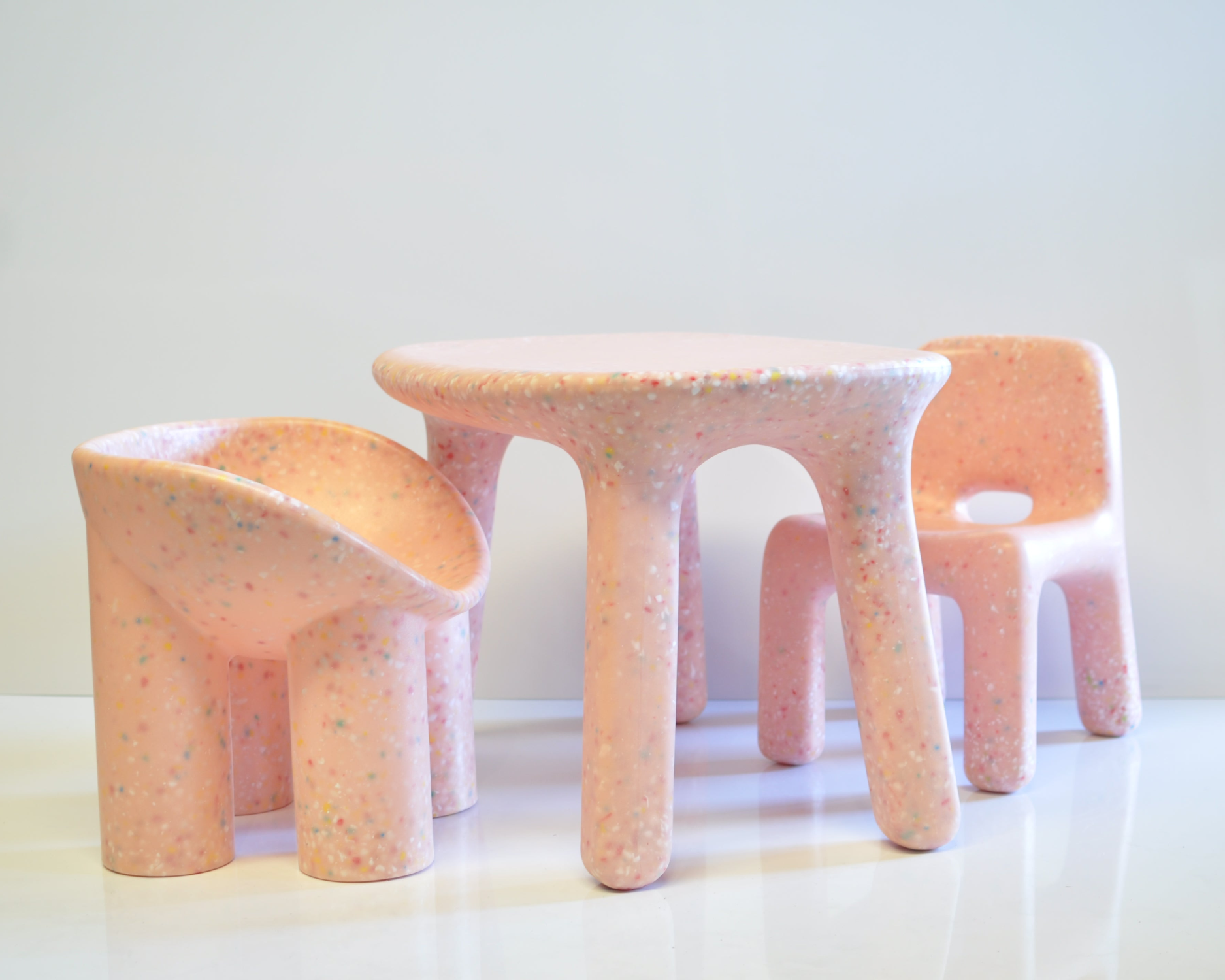 Set of pink confetti kids chairs with a textured surface on a white background