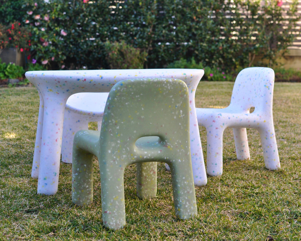 Children's outdoor furniture set on grass with a garden background