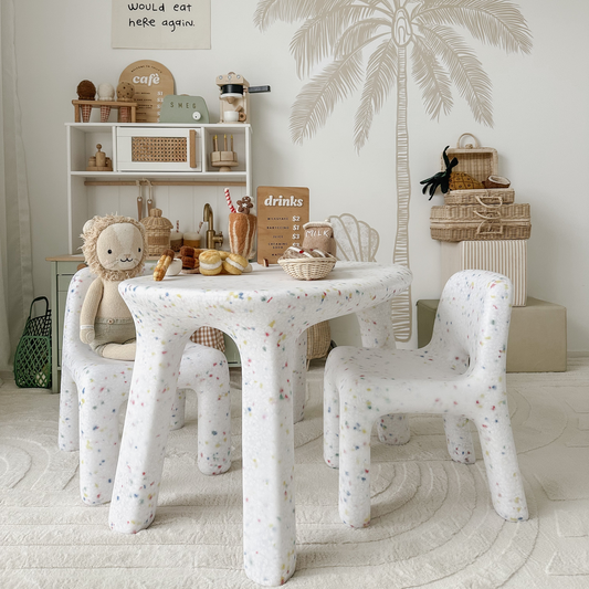 Children's playroom with a white confetti table and chairs, toys, and decorative items.