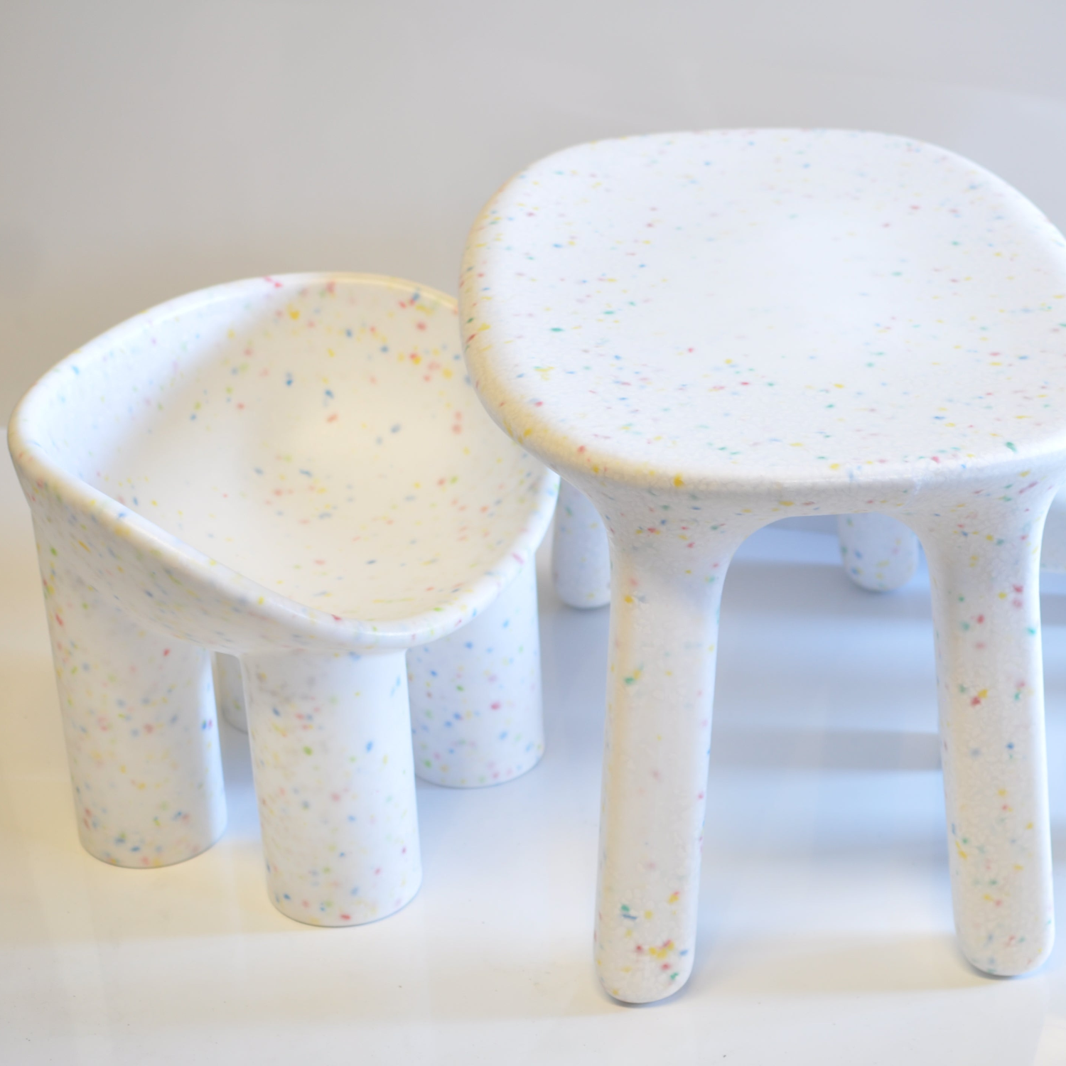 white table and white roly poly chair with a speckled pattern on a light background