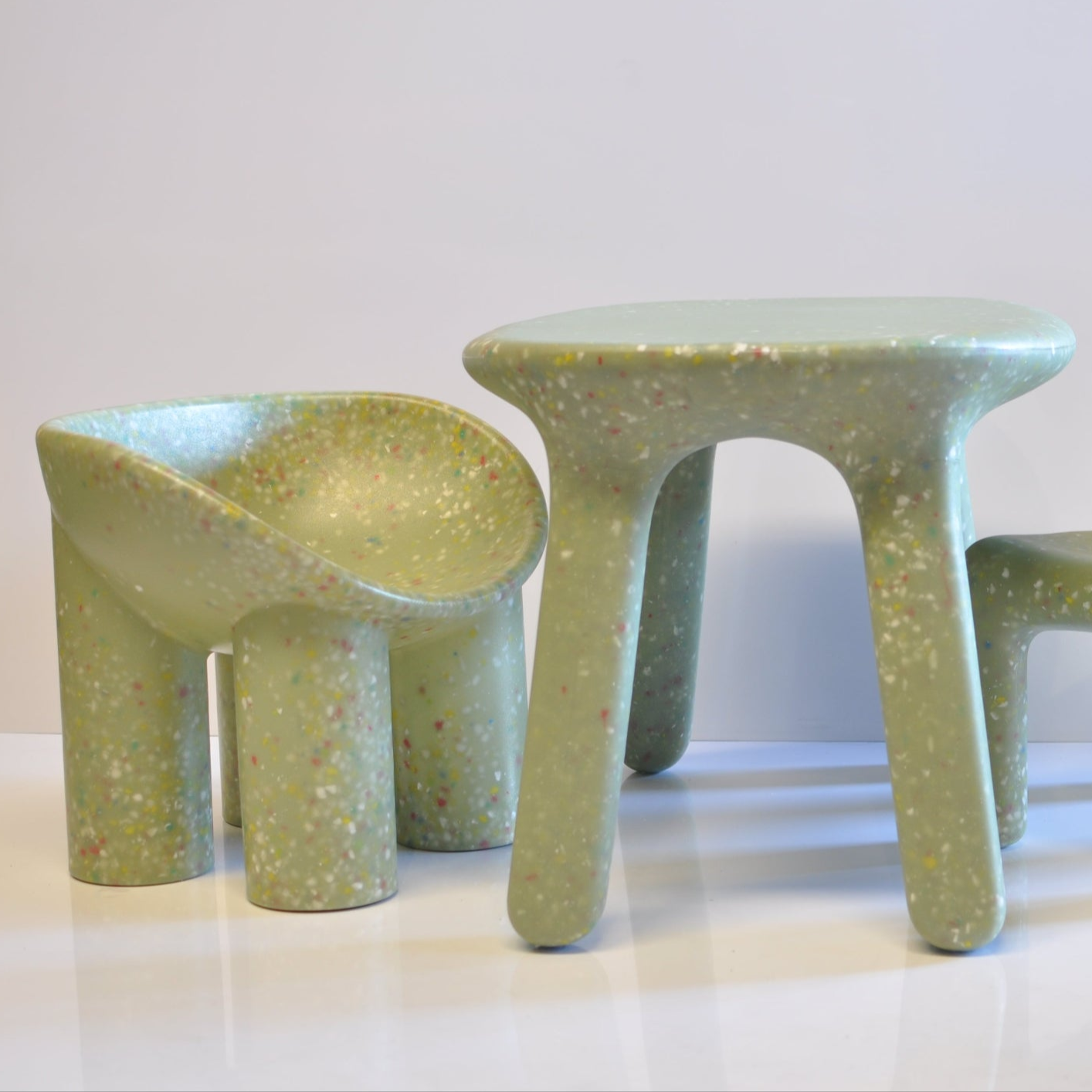 green confetti table and roly poly childrens chair on a white grey background