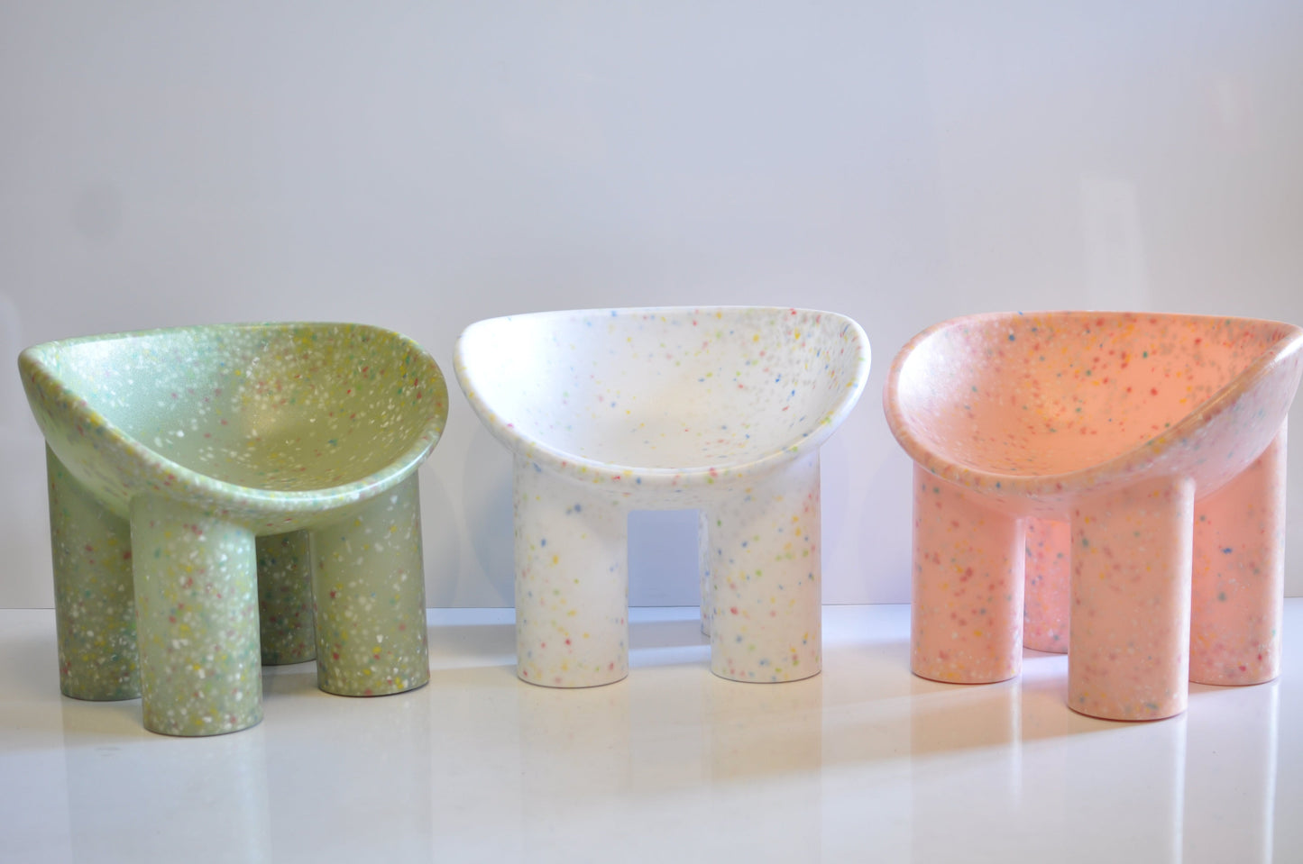 Three colorful roly poly chairs on a white surface with a light gray background