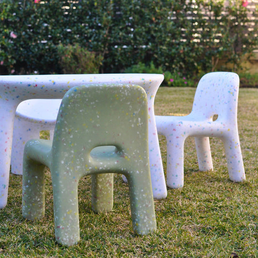 Children's outdoor furniture set on grass with a garden background