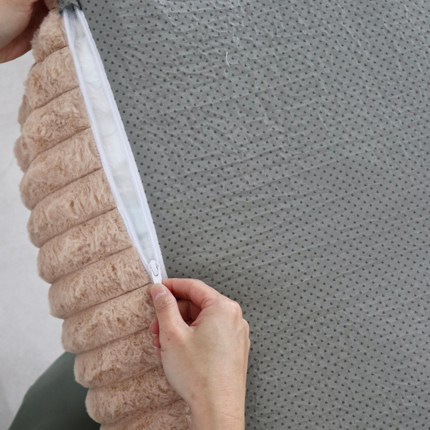 Person holding a textured beige kids couch mini lounger against a gray textured background