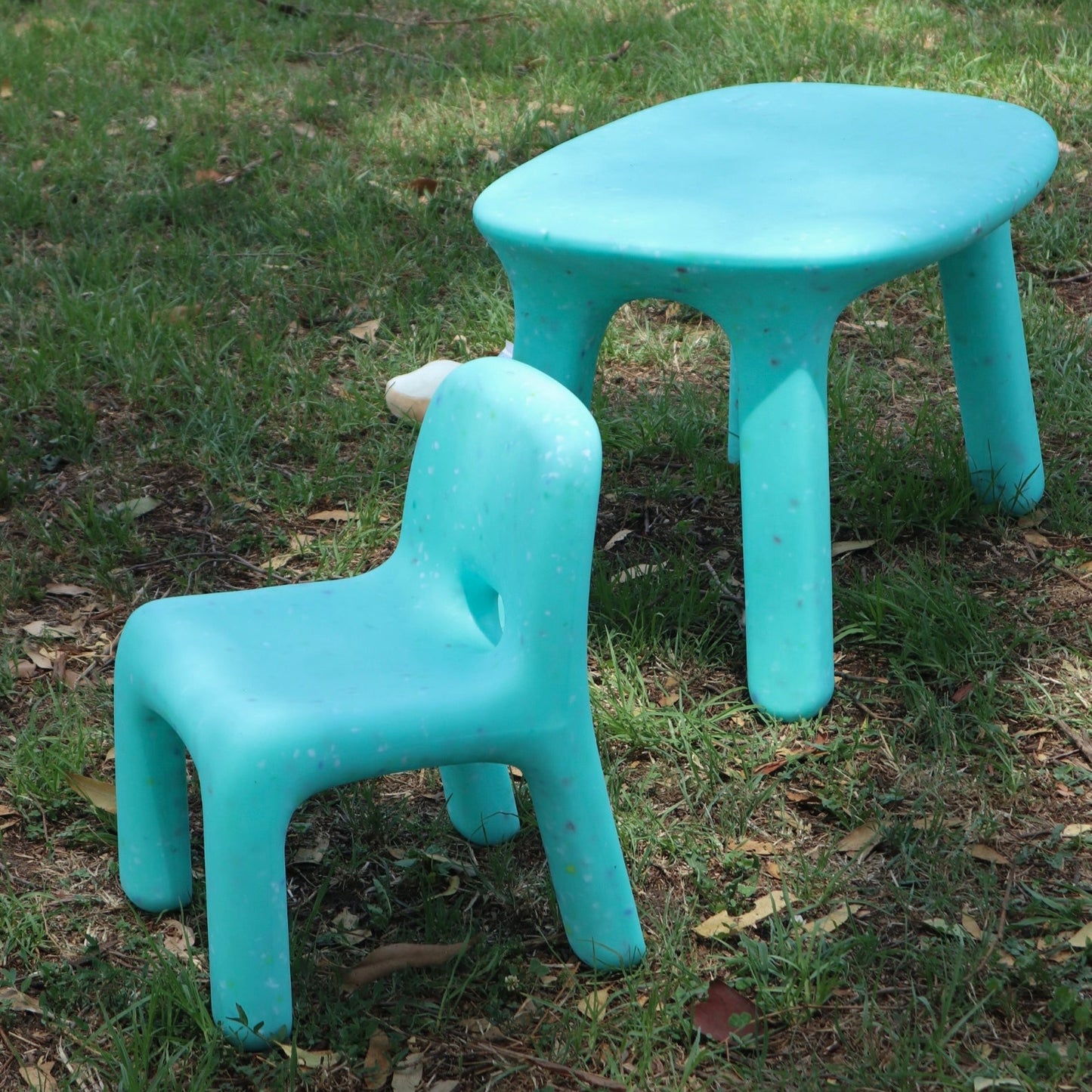 Two turquoise children's chairs and a table on grass